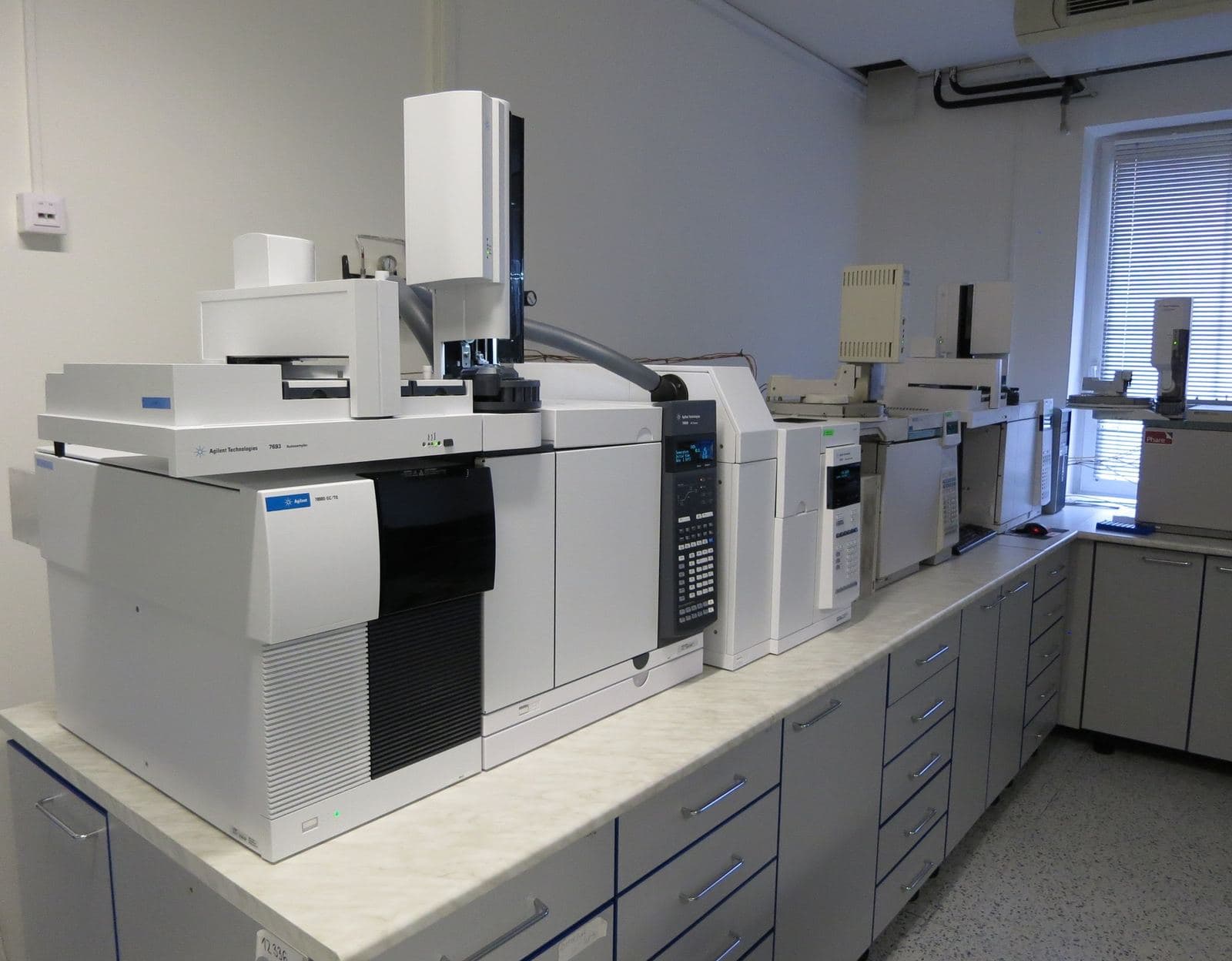 A row of gas chromatographs on a bench in a food inspection laboratory.