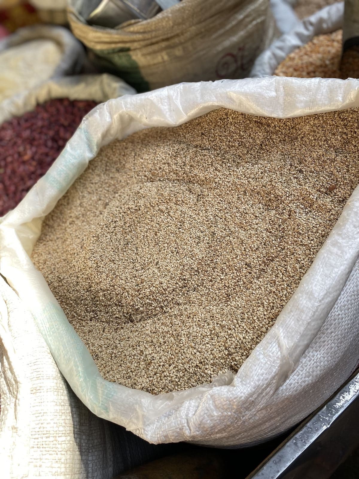 An open sack of hulled sesame seed at a market stall.